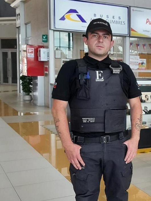 Guardia de Estrategia Security con uniforme y chaleco en el hall de un terminal de buses